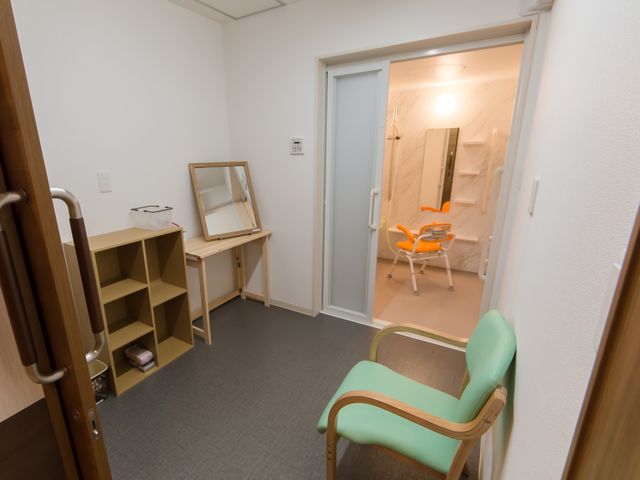 居室のドレッサーと入口 脱衣所 居心地の良い居室で、広々とした入口からは明るい浴室が見え、個人の時間を大切にできる環境が整っています。