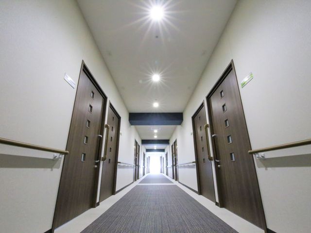 廊下の明るい照明 廊下 手すりが整った清潔感のある廊下が広がり、静かな雰囲気の中で働く環境が整っています。
