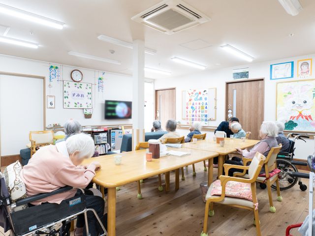 和やかな共有スペース 共有スペース 木のぬくもりが感じられる広々とした食堂です。ここでは、利用者の方々が自由に過ごす様子が見受けられ、絵画や飾りが空間に彩りを添えています。