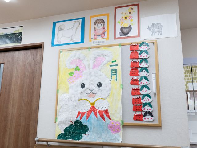 壁に掛けられた手作り絵画 廊下 手作りの温もり溢れる絵画や工作品が壁を飾り、訪れる方々に心和むひとときを提供しています。