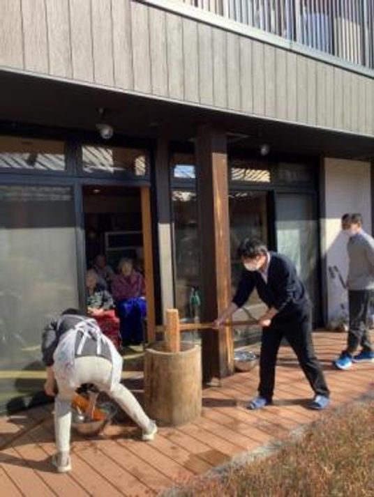 玄関前で餅つきをする人々