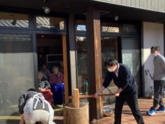 玄関前で餅つきをする人々 庭 庭先で行われている餅つきの様子です。住人も一緒に伝統的な体験を楽しめます。