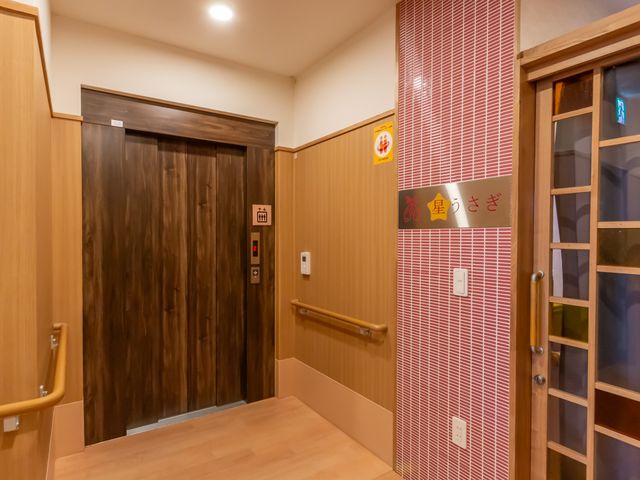 落ち着いた色調の廊下 廊下 木目調の落ち着いた廊下です。エレベーターは車椅子にも配慮した設計になっています。