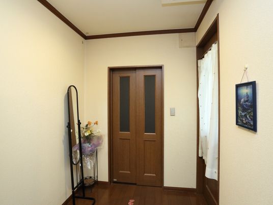 エレベーター前は、クリームと茶ベースの落ち着いた雰囲気である。壁際には鏡が設けられ、その脇に花が飾られている。