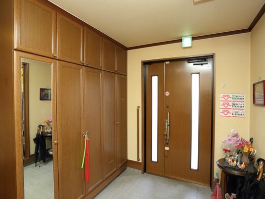 玄関の入り口は、非常用出口としても利用できる。ドアにスリットがあるため、自然光が入って来ていつも明るい。収納棚とサイドボードが見られる。
