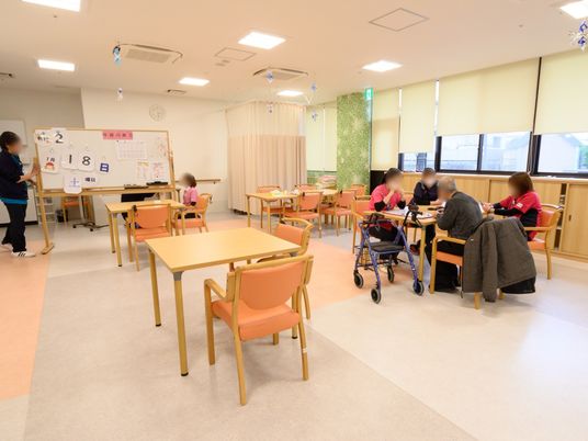 ラウンジでは入居者様が長い時間を過ごすので、休憩用のベッドが奥に設置されている。天井からはモビールが吊り下げられ、家庭的で親しみやすい印象。