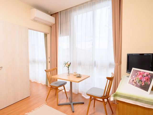 快適な居室の風景 居室 ベッド隣のテーブルにはお花が飾られており、窓辺には柔らかな光が差し込む明るい個室です。ゆったりとくつろげる空間が整い、快適な日々を支援します。