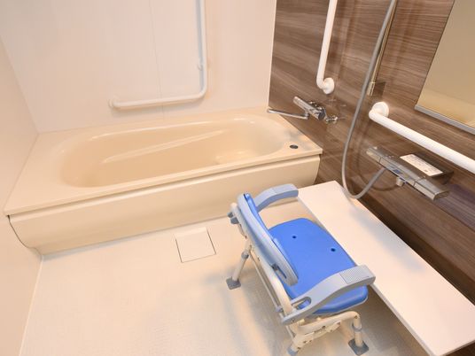 個浴室の中には安全対策として、手すりが多数設置されている。洗い場には肘置き付きのシャワーチェアーも完備している。