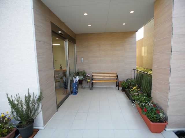 屋外ベンチと植物のエントランス 玄関 快適なエントランスが、心地よい出迎えをしてくれます。花々と緑に囲まれたベンチは、訪れる人々に穏やかな時を提供します。