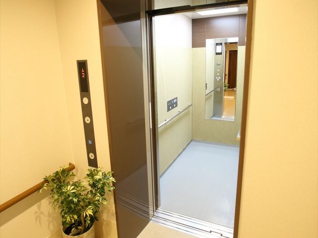 エレベーター前の廊下 エレベーター 手すり付きの廊下に面したエレベーターは、ゆったりとしたスペースで待ち時間も安心です。車椅子の方も安心して移動できる設計になっています。