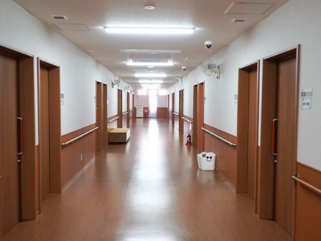 清潔な廊下の様子 廊下 手すりが設置された広々とした通路です。落ち着いた色合いで、安らぎを感じる空間が広がっています。