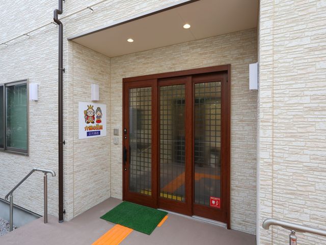 エントランス外観と看板 玄関 バリアフリー設計の明るい入口では、安心してお過ごしいただけます。職員の温かみある迎えの準備が整っています。
