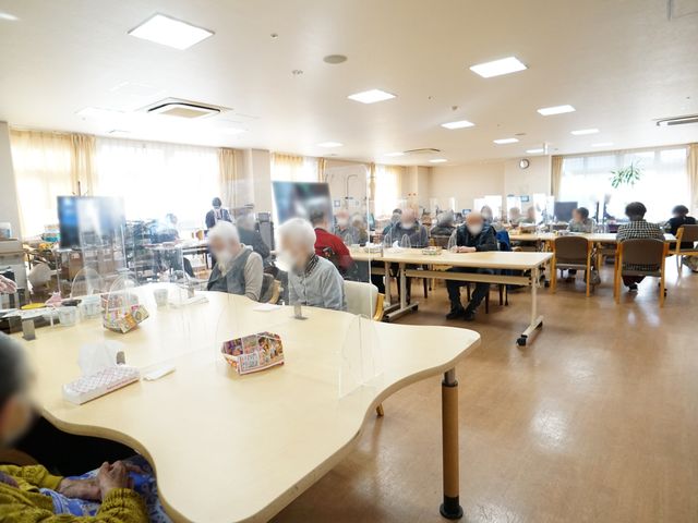 利用者の憩いの場所 共有スペース ゆとりを感じる開放的な空間で、利用者が食事や憩いの時間を過ごしています。あたたかな光が差し込む、居心地の良い場所です。