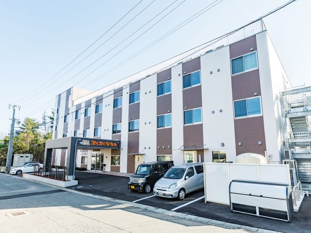 清潔な外観の建物 外観 ゆったりとした駐車スペースが確保された建物前です。ご利用者様の来訪も、家族の送迎も安心して行える設計になっています。
