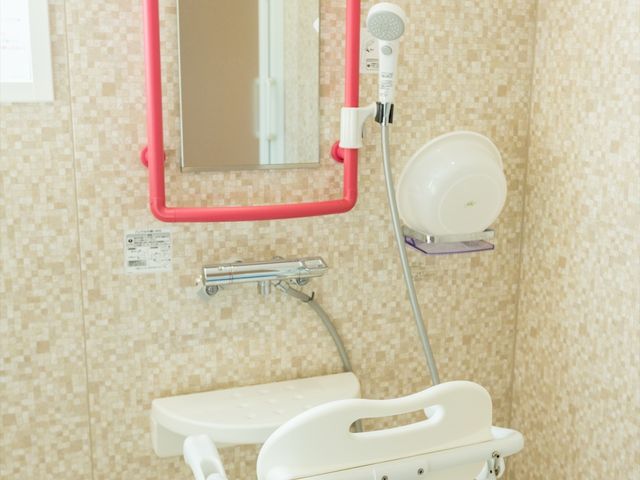 バリアフリー設計の浴室 浴室 サポートバーが施された清潔感のある浴室です。利用者の安全を考慮して座りやすいシャワーチェアも設置されています。