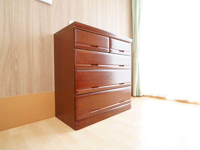 整頓された居室のチェスト 居室 丁寧に磨かれた木目のチェストが、居室の一角に設置されており、生活感が感じられる空間です。