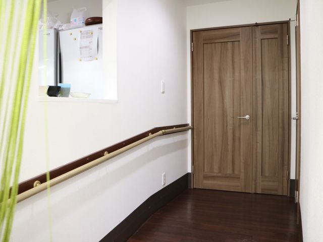 廊下と木製扉 通路 手すり完備の廊下は、安全な移動を支える設計になっており、どなたでも安心してお過ごしいただけます。