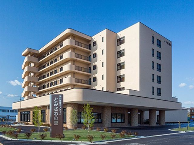 施設外観 外観   青空の下に建つ大きな建物で、明るく開放的な印象です。エントランス前には植栽があり、落ち着いた雰囲気です。