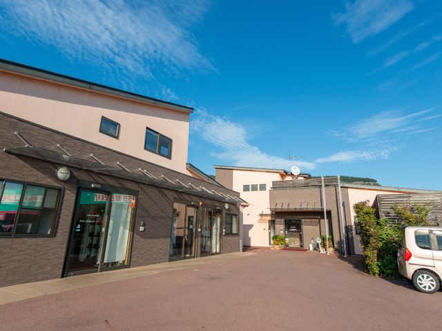 明るい外観の建物 外観 広々とした駐車場と入り口のある快適な施設です。清潔感のある建物外観が、訪れる方々へ安心感を与えます。