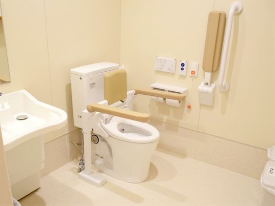 便器の両側に手すりがついた介護仕様のトイレ。壁に緊急コールが取り付けられている