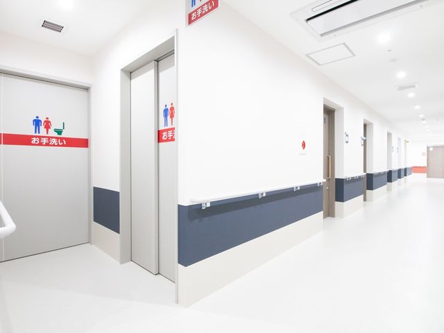 清潔感ある廊下と扉たち トイレ 広々とした廊下は、清掃が行き届いており、患者様の移動もしやすい設計です。安全に配慮した手すりも設置されています。