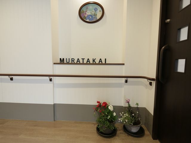 施設のエントランス表示 廊下 落ち着いた雰囲気のエントランスには、訪れる人を優しく迎える植物が配置されており、明るく清潔感のある出迎えができる空間となっています。