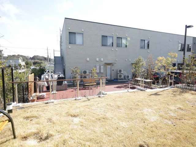 施設と庭がある景色 リハビリスペース 開放的な庭が印象的な施設でのびのびとした環境でお仕事しませんか。自然の光がたっぷりと注ぐ明るい経路もあります。