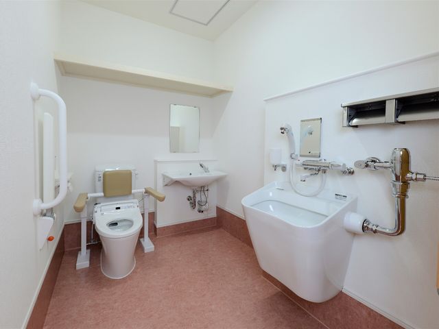 バリアフリーの洗面所設備 トイレ サポートバーが設置された清潔なトイレです。手すりや広々としたスペースで、どなたも安心してご利用いただけます。
