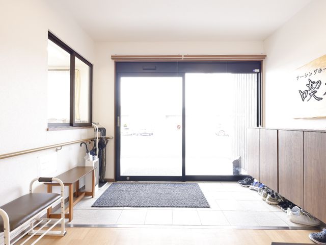 明るいエントランスの手前 玄関 手すり付きで明るいエントランスは、皆様の快適な出入りをサポートしております。安心してご利用いただける配慮が行き届いています。