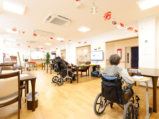 明るい居室内の様子 リビングダイニング 広々とした居室で、利用者がそれぞれの活動を行っています。共有スペースは椅子配置が工夫され、ゆったりとした時間を過ごせる設計です。