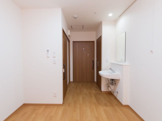 清潔感のある廊下 居室 廊下は木目調の床で、洗面台も設置されており、清潔感があります。気持ちよく仕事をするための環境が整っています。