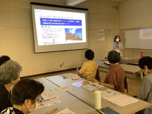 勉強会に参加する利用者たち 多目的室 多目的室で行われる勉強会の様子です。参加者が資料を見ながら説明に耳を傾けています。