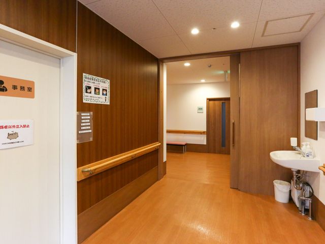 廊下の手すりと居室 居室 明るく清潔な施設内で、手すりのある廊下を通り、入居者の方々の居室のサポートを行います。