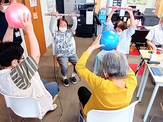 楽しげな様子の多目的室 多目的室 笑顔でボールを持ち上げる利用者様がいる、交流と活動の場です。多世代が集い、心地よい時間を過ごしています。