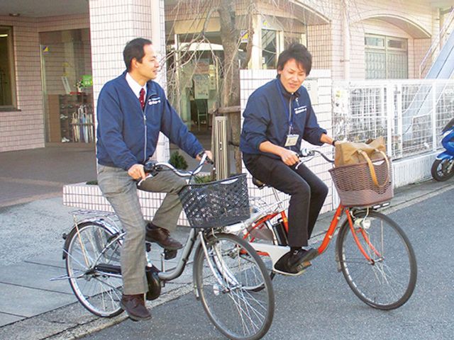 スタッフの笑顔と自転車 スタッフイメージ 笑顔で自転車に乗るスタッフの姿から、温かい雰囲気が伝わります。利用者様のサポートに日々尽力しています。