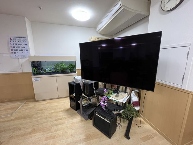 設備が充実したスペース リビング 広々としたリビング空間には、大型テレビと観葉植物が配置され、リラックスできます。