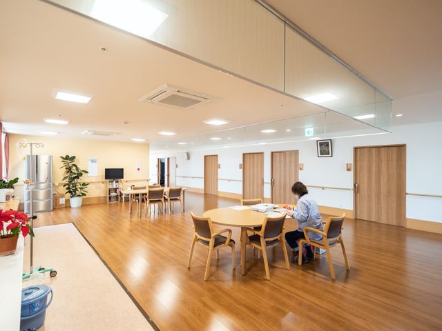 広々とした快適な食堂 共有スペース 広々としたダイニングルームで一人の方がゆったりと食事をされており、穏やかな時間が流れています。ゆとりの空間は心地よさをもたらし、快適な食事のひと時を提供しています。