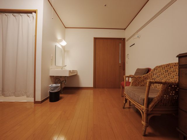 洗面台のある部屋 居室 広々とした居室には、木製の床と快適な座席があり、リラックスできる空間が広がっています。