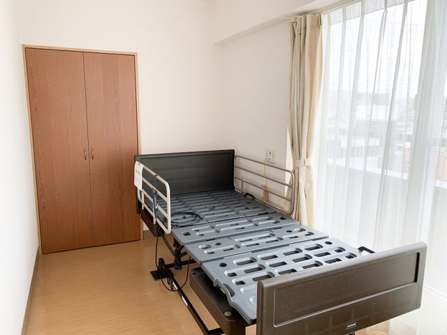 居室の安全なベッド 居室 手すり付きのベッドが特徴の居室で、明るい窓辺が安心感を提供します。安全かつ快適な日々を過ごせる空間です。