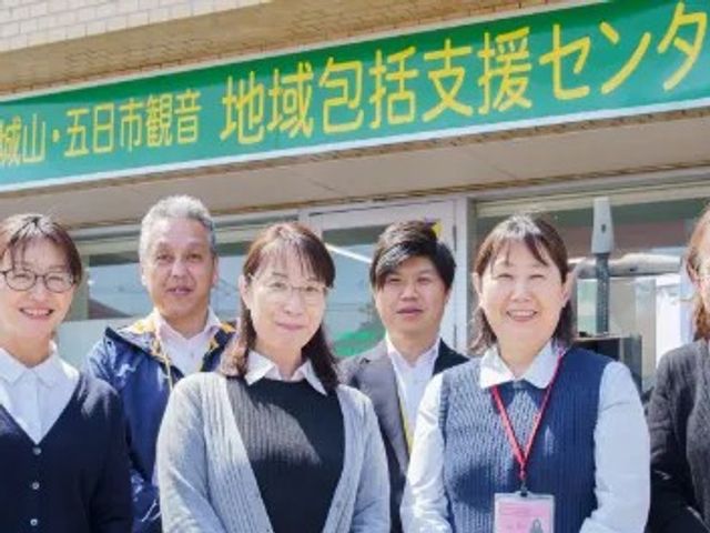 スタッフが並ぶ外観前 外観   施設の前でスタッフの方々が並んでおり、明るい雰囲気が伝わります。見学や就業を考える方にも、職場の印象をつかみやすいです。