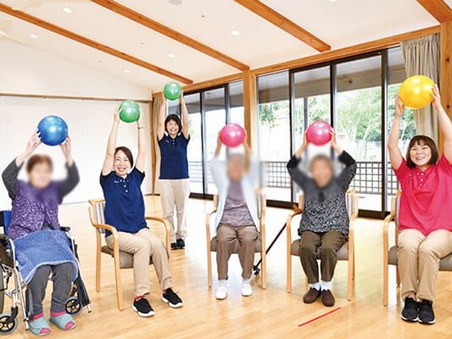 リハビリ室 機能訓練室 自然光が差し込む空間で椅子に座って楽しみながら体を動かす様子が見られます。