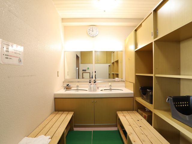 清潔な洗面台と棚 脱衣スペース シンプルで清潔感あふれる洗面スペースは、利用者の快適な日常生活を支えます。整理整頓もしやすい広々とした棚が特徴です。