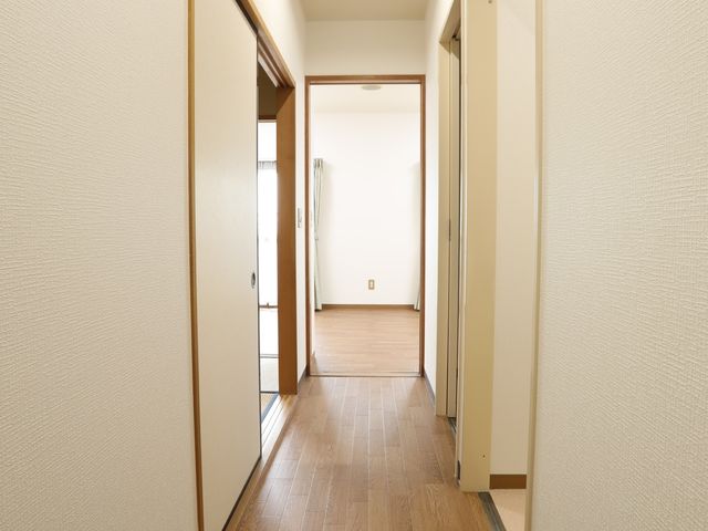 清潔な室内の廊下 居室 落ち着いた色合いの廊下は、清潔感があり、安心して働く環境を提供します。明るい照明が、安全で快適な移動を支えています。