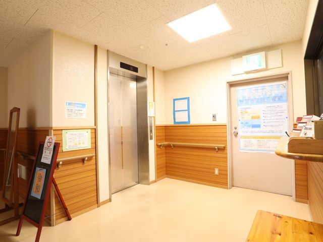 廊下とエレベーターの様子 廊下 清潔感のある明るい廊下には、案内板が設置されており、スムーズな移動が可能です。エレベーターの近くには、利便性を考慮した休憩スペースも備わっています。