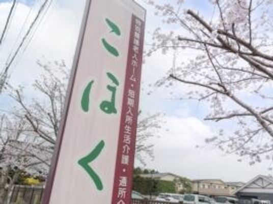施設看板と桜並木の外観  