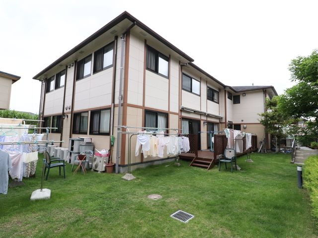 緑の芝生と建物外観 入口 広々とした緑あふれる環境で、日々の暮らしが心地よく感じられる空間です。清潔感のある建物周辺は、ゆとりをもって生活できます。