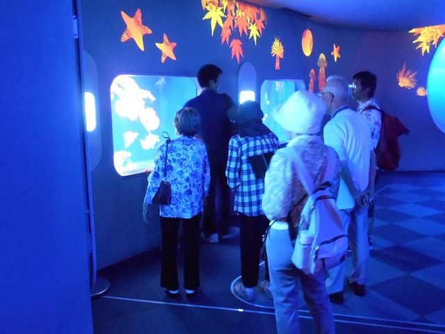 水槽のある室内 多目的室 明るい照明が幻想的な雰囲気を作る空間です。多くの方が興味深そうに展示を楽しんでいます。