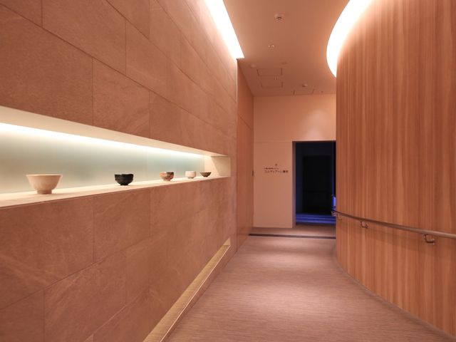 落ち着いた廊下の風景 廊下  ゆったりとした空間の廊下は、暖色の照明で落ち着いた雰囲気を演出し、壁一面には美しい作品が展示されています。