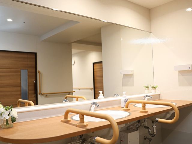 洗面台の装飾と設備 洗面所 手すり付きの洗面台は利用しやすく、壁には季節感を感じさせる装飾が施されています。