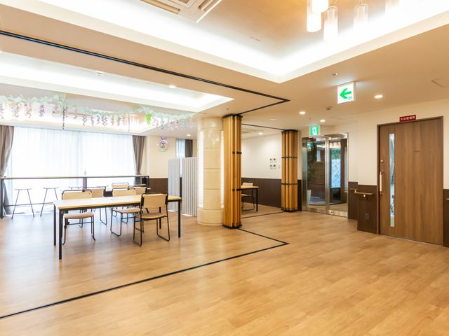 広々とした室内空間 内観 広々とした空間で、自然光が差し込む明るい場所です。テーブルと椅子が配置されています。